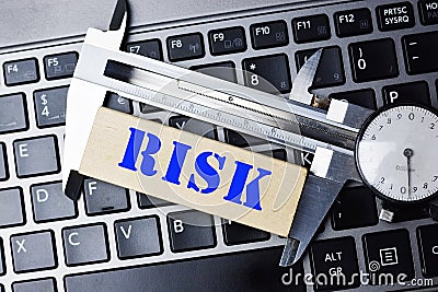 Measuring the risk concept with high precision caliper tool on laptop keyboard Stock Photo