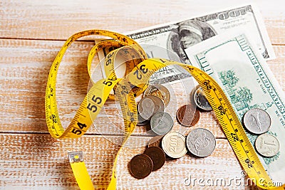 Measuring tape, coins and dollar bills on the table Stock Photo