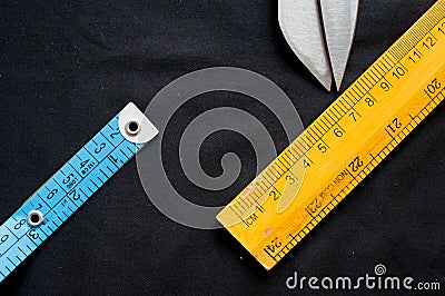 Measuring tape, scale and scissors on black cloth Stock Photo