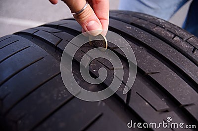 Measuring tire depth using a small coin Stock Photo