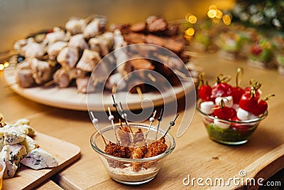 Meat canapes of chicken in walnut sauce, assortment of meat kebabs on large wooden skewers, caprese canapes in pesto sauce Stock Photo