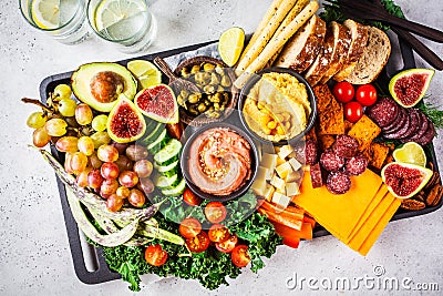 Meat and cheese appetizer platter. Sausage, cheese, hummus, vegetables, fruits and bread on black tray Stock Photo