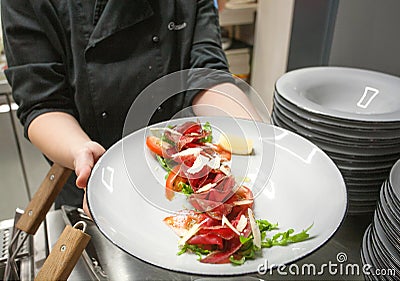 Meat dish in hand of chef, plate of tasty Carpaccio for hungry visitors of a restaurant Editorial Stock Photo