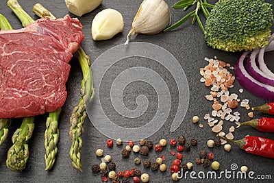 Meat food : raw beef fillet on black stone board with asparagus with dry spices ready to cooking Stock Photo