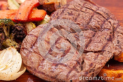 Meat grilled ribai with vegetables. Ribai steak on wooden board. Close up Stock Photo
