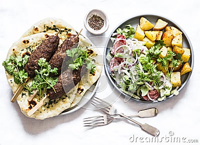 Meat kebab, garlic herb naan, yogurt dressing vegetable salad, roasted potatoes - delicious lunch, tapas, snack in the Stock Photo