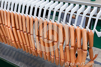 Meat sausages on plastic conveyer in food industry Stock Photo