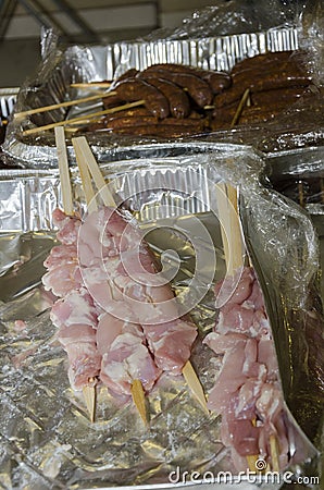 Meat sausages on wooden skewers in Ð°luminium packaging and cellophane Stock Photo