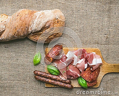 Meat selection / wine set on a rustic wood board over a rough sa Stock Photo