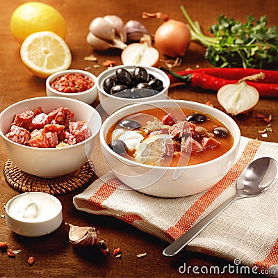 Meat Solyanka soup on with ingridients, sausage, olive,lemon, parsley, garlic, yogurt. Ukrainian food. Wooden background Stock Photo