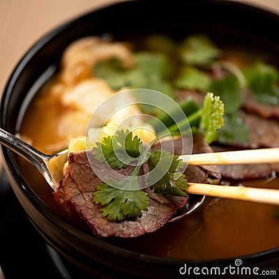 Meat thai soup with onion and parsley. Close up shot. Eating lunch with chopsticks. Spicy oriental dish, Pan-Asian Stock Photo
