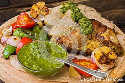 Meat with vegetables, grilled and served Italian Salsa Verde sauce. Wooden rustic table. Close-up Stock Photo