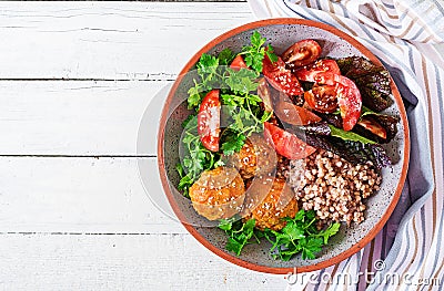 Meatballs, salad of tomatoes and buckwheat porridge on white wooden table. Healthy food. Diet meal. Buddha bowl. Top view. Stock Photo