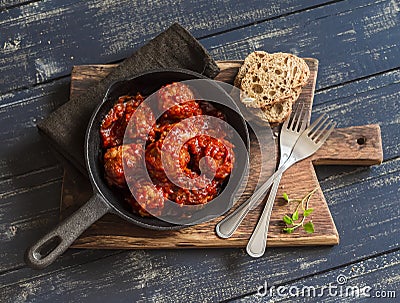 Meatballs in tomato sauce in a pan on rustic wooden cutting board Stock Photo