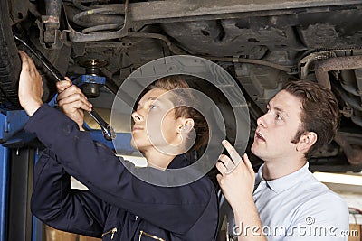 Mechanic And Apprentice Working On Car Together Stock Photo