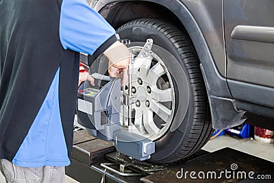 Mechanic attaching the wheel alignment device onto the wheel at workshop Stock Photo