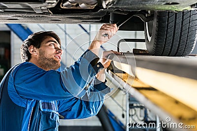 Mechanic Changing Tire From Suspended Car At Automobile Shop Stock Photo