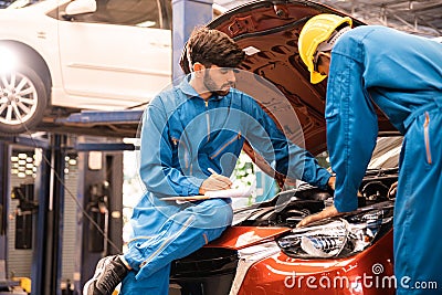 Mechanic checking the opened hood car with his assistant. Auto car repair service center. Professional service Stock Photo