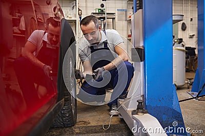 Mechanic Checking Tire Pressure in Auto Shop Stock Photo