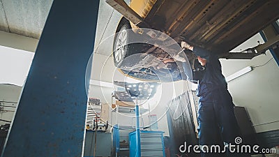 Mechanic checks bottom of the car in Garage mechanical workshop - lifted auto standing in automobile service Stock Photo