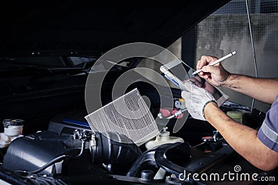 The mechanic checks the engine using tablet computer technology. Complete with wrench tool Auto mechanic working in the garage. Stock Photo