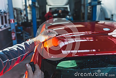 Mechanic customizes car removing spoiler using cutting cord in auto repair shop Stock Photo