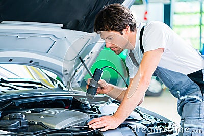 Mechanic with diagnostic tool in car workshop Stock Photo
