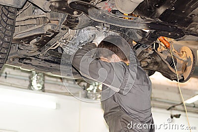 Mechanic in a dirty uniform repairs a car Stock Photo