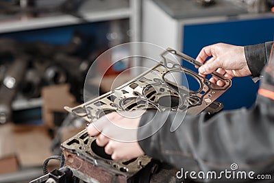 Sealing gasket in hand. The mechanic disassemble block engine vehicle. Engine on a repair stand with piston and Stock Photo