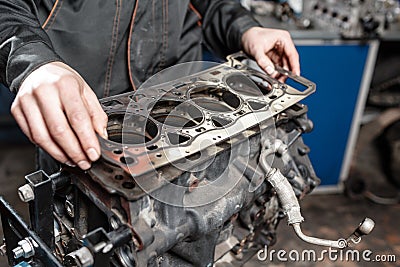 Sealing gasket in hand. The mechanic disassemble block engine vehicle. Engine on a repair stand with piston and Stock Photo