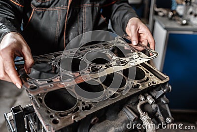 Sealing gasket in hand. The mechanic disassemble block engine vehicle. Engine on a repair stand with piston and Stock Photo