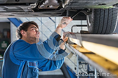 Mechanic examining the suspension of a car during a MOT Test Stock Photo