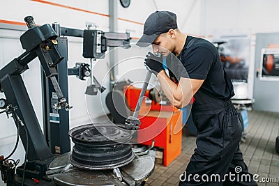 Mechanic fixing broken wheel, tire service Stock Photo