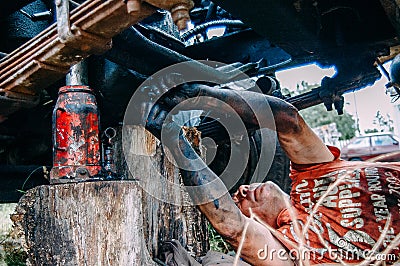 Mechanic fixing a car outside with dirty hands Editorial Stock Photo