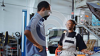 Mechanic in garage fixes customers car Stock Photo