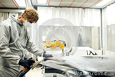 Mechanic grinds car part for painting. Car body work auto repair paint after accident Stock Photo