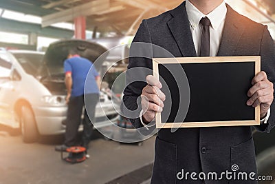 Mechanic hand checking and fixing a broken car in garage.Inspec Stock Photo