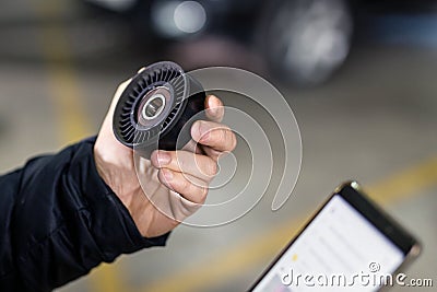 Mechanic hand holding car spare part and ordering new one via smartphone. Vehicle maintenance and service statio Stock Photo