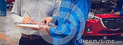 Mechanic holding clipboard with car owner in the workshop garage. Car auto services concepts. Close-up Stock Photo
