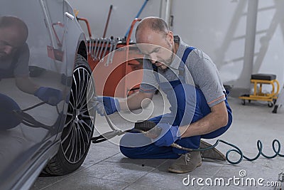 Mechanic inflating a tire and checking air pressure with a gauge Stock Photo