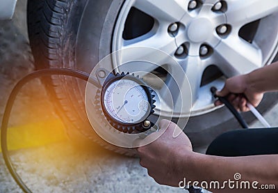 Mechanic inflating tire and checking air pressure with gauge pressure Stock Photo