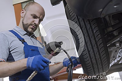 Mechanic inflating a tire and checking air pressure with a pressure gauge Stock Photo