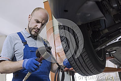 Mechanic inflating a tire and checking air pressure with a pressure gauge Stock Photo