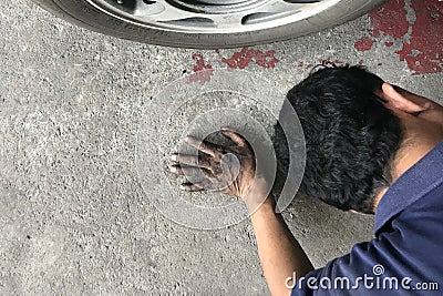 Mechanic laying behind car and looking under car Stock Photo