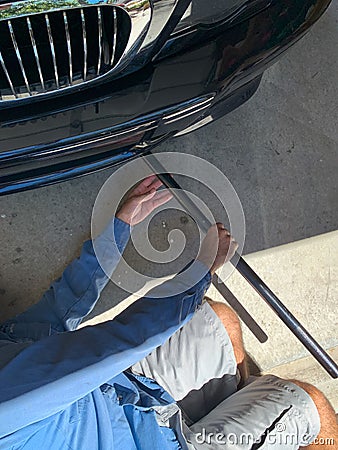 Mechanic Laying on Floor to jack up Car Stock Photo