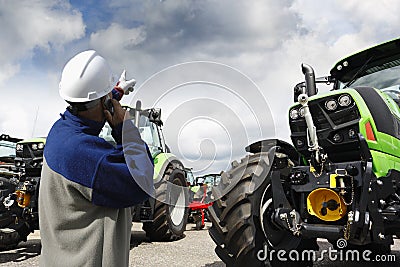 Mechanic pointing at large farming tractors Stock Photo