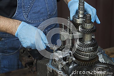 Mechanic repairing the car`s gearbox. Unscrewing a socket with a damaged gearbox. Stock Photo