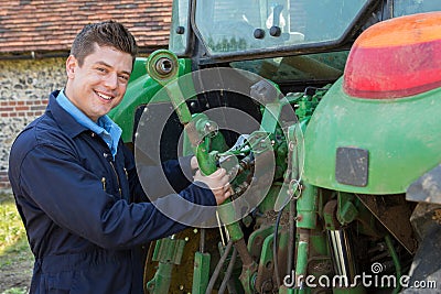 Portrait Of Mechanic Repairing Tractor On Farm Stock Photo