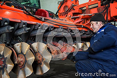 Mechanic repairs agricultural machinery. Preparation of equipment for field work Editorial Stock Photo