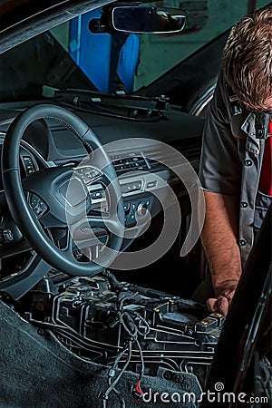 A mechanic repairs a luxury SUV Repair wiring, gearboxes, disassembled interior premium crossover. Removed chairs. Leather Stock Photo
